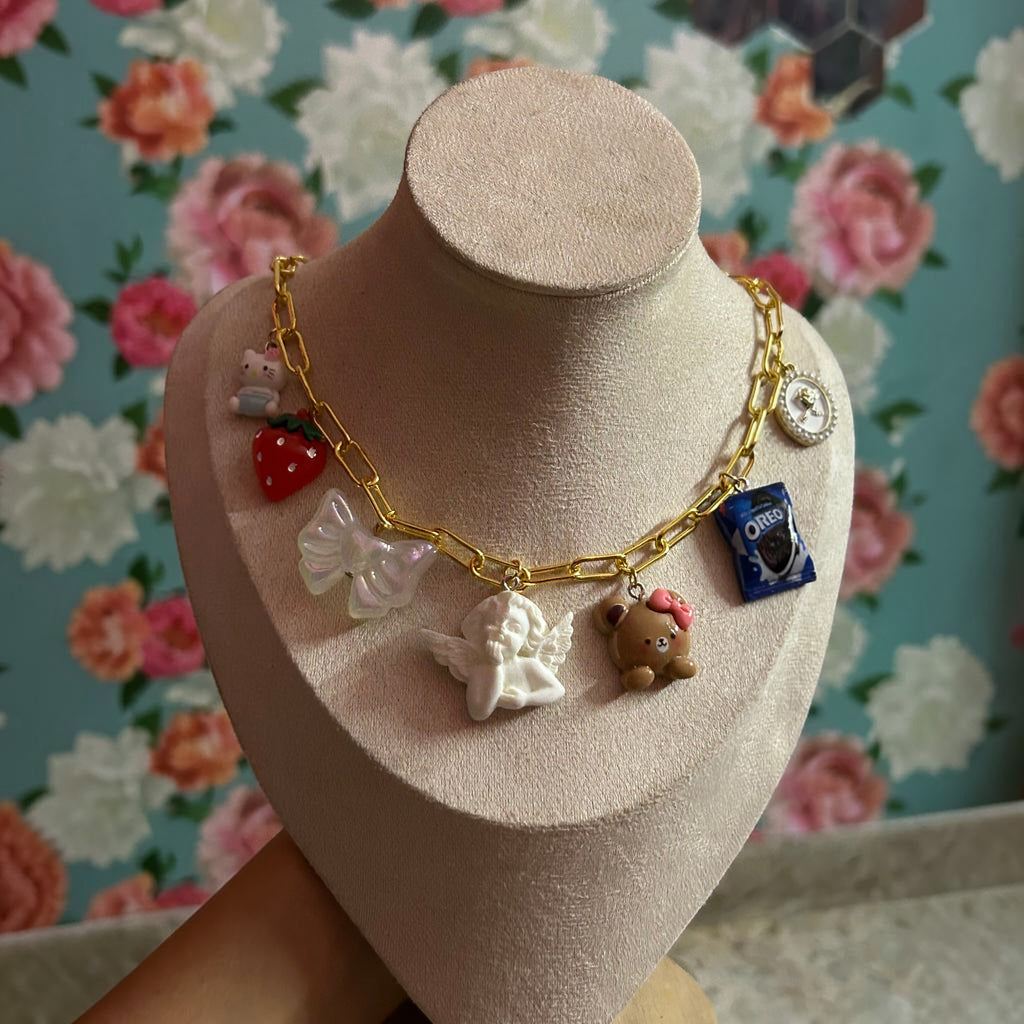 Pretty Gorgeous Stuff gold chain necklace with angel, teddy bear, strawberry and cookie charms close-up