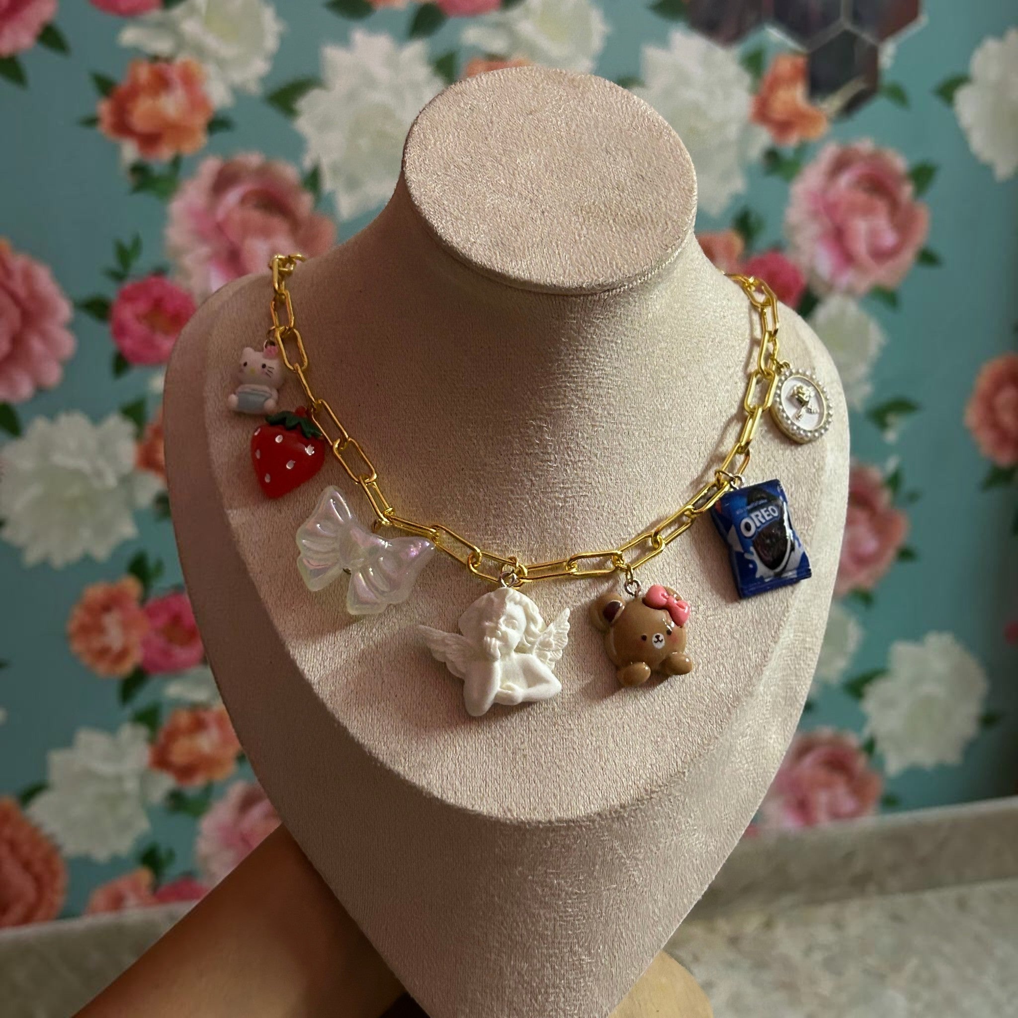 Pretty Gorgeous Stuff gold chain necklace with angel, teddy bear, strawberry and cookie charms close-up
